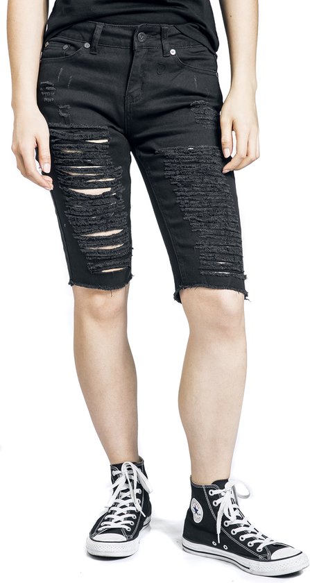 Zijzicht van een vrouw in zwarte, opengescheurde bermudashorts met rafelige zoom.