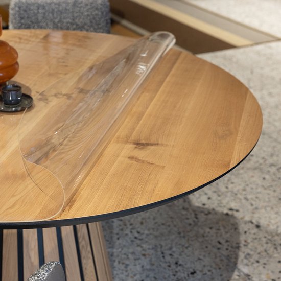 Ronde houten tafel met een transparante beschermhoes.