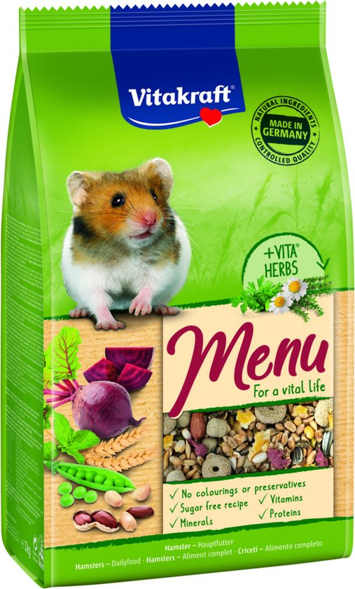 Groene zak Vitakraft Menu Vital hamstervoer. Een hamster zit naast bieten, erwten, tarwe en een mix van zaden. Gemaakt in Duitsland.