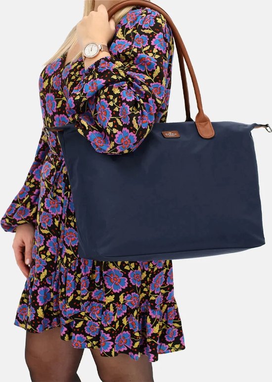 Blauw fluwelen jurkje met bloemenprint, draagt een donkerblauwe nylon tas met bruine handvatten.