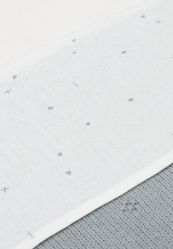 Lichtblauwe wiegdeken met een patroon van kleine blauwe sterretjes en kruisjes op een witte ondergrond.