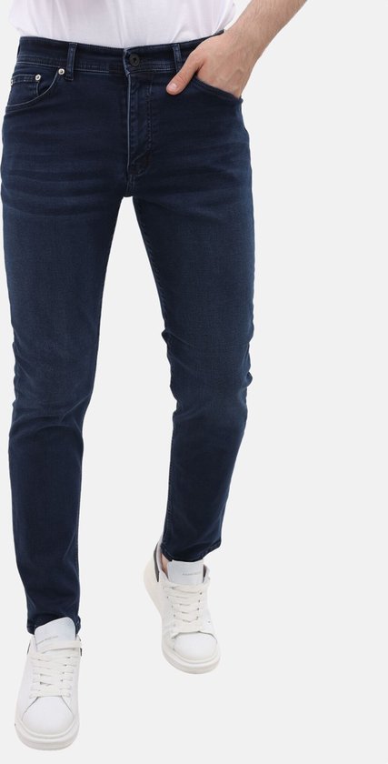 Blauwe stretch jeans met regular fit voor heren. Gedragen met witte sneakers.