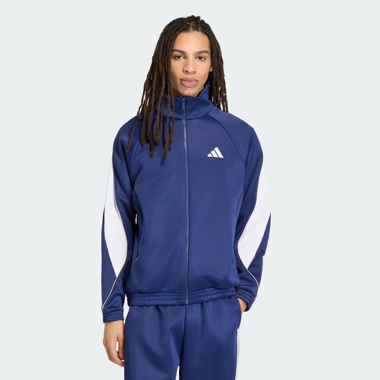Man met dreadlocks in een donkerblauwe sportjack met witte mouwaccenten en bijpassende broek.