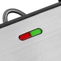 Close-up van een roestvrijstalen contactgrill met een rode en groene indicatorlamp.