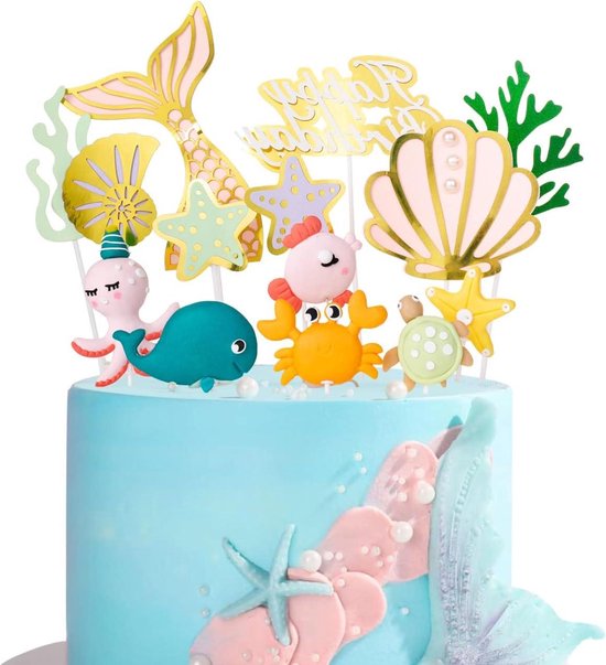 Een blauwe taart versierd met zeedieren taarttoppers, waaronder een walvis, octopus, vis, krab, schildpad, zeemeerminstaart en schelp.