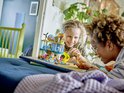 Twee kinderen spelen met een LEGO Friends speelset van een zee reddingscentrum, met speelgoed figuren en dieren.