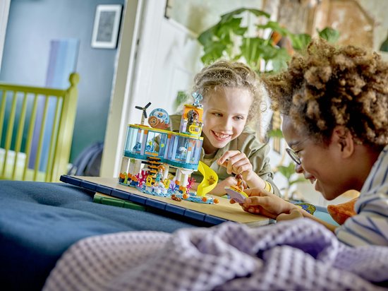 Twee kinderen spelen met een LEGO Friends speelset van een zee reddingscentrum, met speelgoed figuren en dieren.