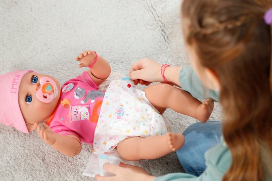 BABY born Emma pop liggend op een kleed, met speen, in roze outfit. Een kindje wisselt de luier.