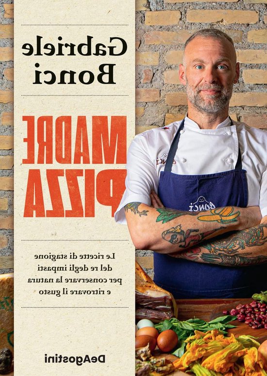 Chef met tatoeages en een schort met 'BONCI' erop, staand voor een bakstenen muur.