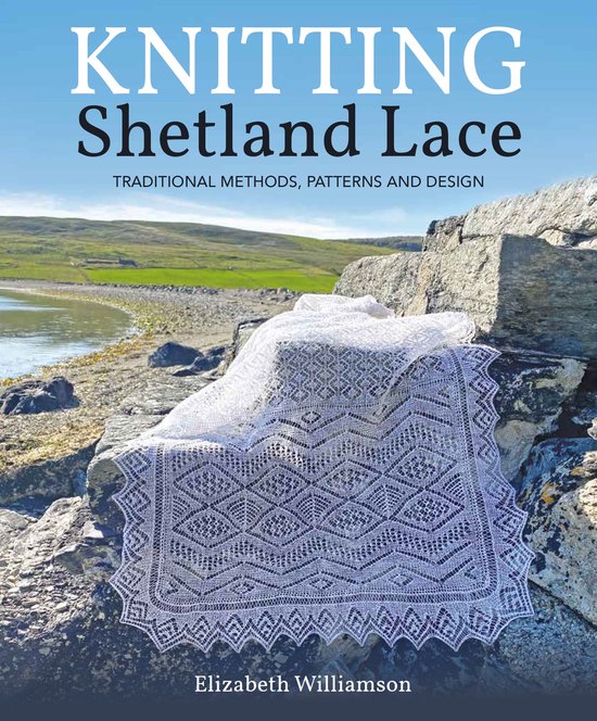 Boek kaft "KNITTING Shetland Lace" met een wit kanten sjaal op stenen bij de zee.