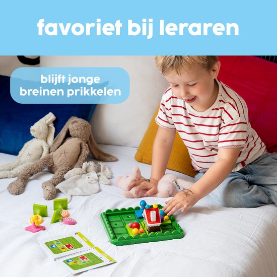 Een jongen speelt geconcentreerd met het spel Hans & Grietje op een wit bed. Op het speelbord staan een huisje, personages en gekleurde ballen.