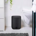 Zwarte pedaalemmer naast een toilet en witte kast in een badkamer.