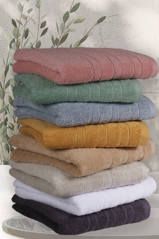 Pile de huit serviettes dans des couleurs comme le vieux rose, le vert, le bleu clair, le moutarde, le beige, le gris, le blanc et le violet foncé.