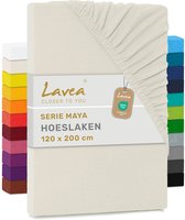 Crème hoeslaken Lavea Serie Maya 120x200cm met stapels gekleurde lakens op de achtergrond.