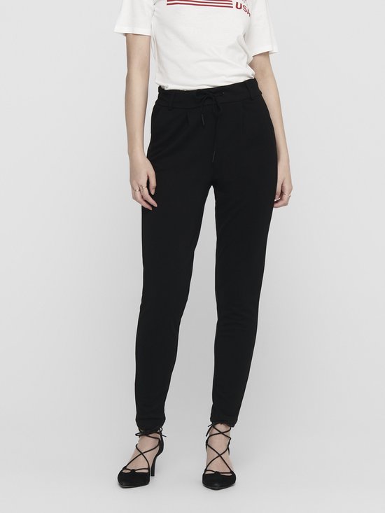 Model in zwarte broek met ceintuur, gedragen met hoge hakken. Close-up van de heupen.