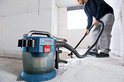 Bosch Professional bouwstofzuiger, blauw en transparant, met man die vloer zuigt in een betonnen ruimte.