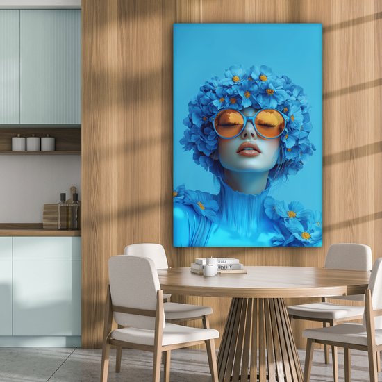 Portrait bleu d'une femme avec des lunettes orange et des fleurs, dans une cuisine-salle à manger.