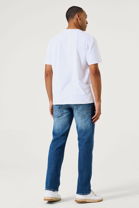 Man met witte T-shirt, van achteren gezien, draagt een blauwe jeans met stonewash.