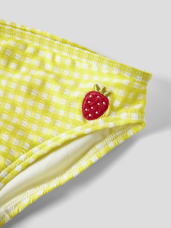 Close-up van een geel geruit bikinibroekje met een geborduurde rode aardbei.