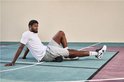 Basketbalspeler Paul George gebruikt een zwarte schuimroller op zijn been op een sportveld.