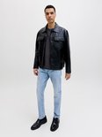 Model in zwart leren jack, grijs t-shirt en lichtblauwe slim fit jeans, volledig zicht.