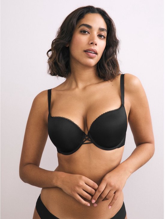 Model in zwarte push-up beha met kanten randjes, handen voor.