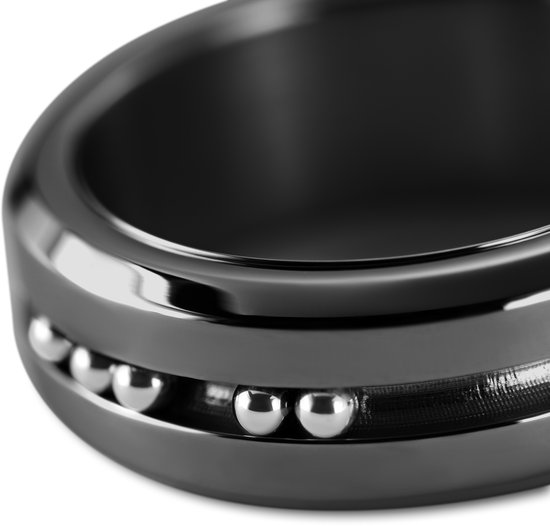 Close-up van een zwarte ring met geribbelde band en zilverkleurige kralen.