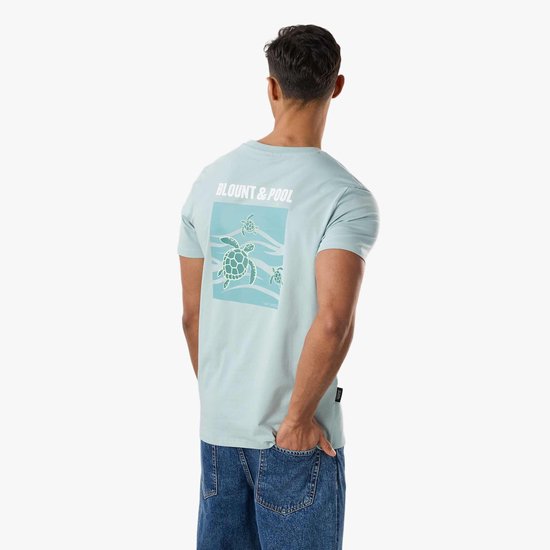 Achterkant van een lichtblauwe T-shirt met grote zeeschildpad-print en 'BLOU NT & POOL' op de rug.