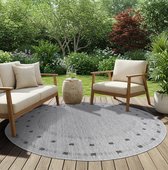 Grijze ronde buitentapijt met zwarte stippen langs de rand, op een houten terras met loungebanken.