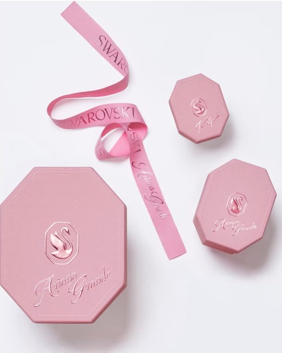 Roze verpakkingen met Ariana Grande en Swarovski logo's, en roze lint.
