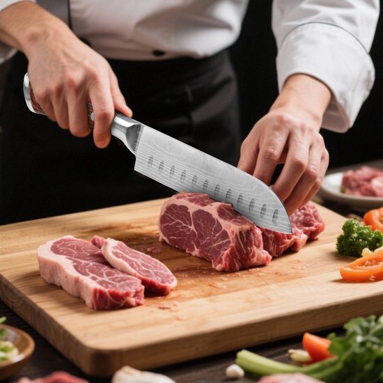 Chef coupant de la viande crue avec un couteau Santoku japonais Damas avec des cavités.