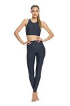 Vrouw met paardenstaart in grijs sporttopje en bijpassende legging, staand.