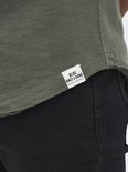Detail van een label met 'BLUE ONLY & SONS' op de zoom van een groene T-shirt.