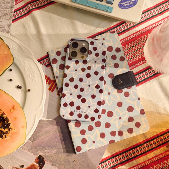 Lichtblauwe telefoonhoes met bruine stippen en beige bloemen, op een gevouwen omslag met hetzelfde patroon.