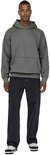 Een man draagt een oversized grijze hoodie en zwarte jeans, frontaal.