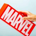 Hand die een rode MARVEL-lamp vasthoudt met witte letters.