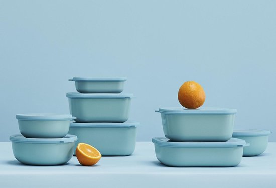 Pile de boîtes et bols bleu clair, avec une orange et une moitié d'orange.