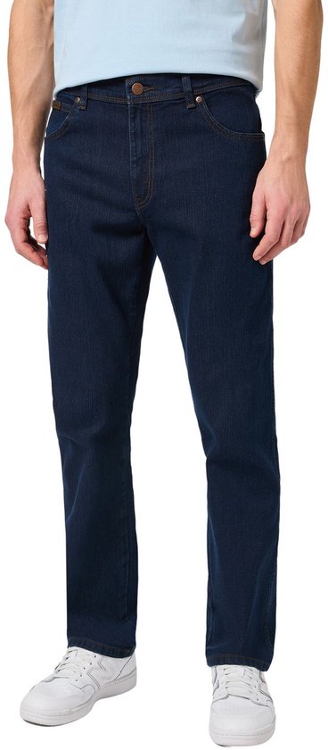 Vooraanzicht van een man in een lichtblauw T-shirt en een donkerblauwe regular fit Wrangler jeans.