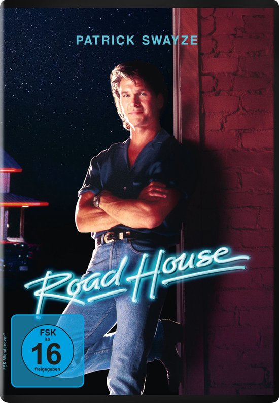 DVD-hoes van 'Road House' met Patrick Swayze, gekleed in een blauwe blouse en spijkerbroek, leunend tegen een bakstenen muur.
