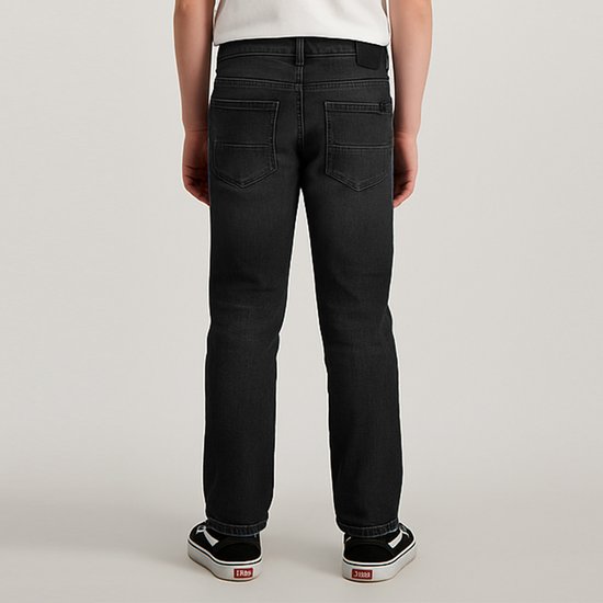 Jongen draagt donkergrijze jeans, achterkant zichtbaar, met witte t-shirt en zwarte sneakers.