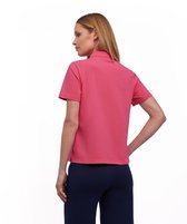 Model met lange blonde haren kijkt over de schouder, draagt een koraalroze Falke poloshirt.