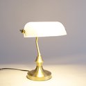 Lampe de bureau dorée avec abat-jour en verre blanc, posée sur une table.