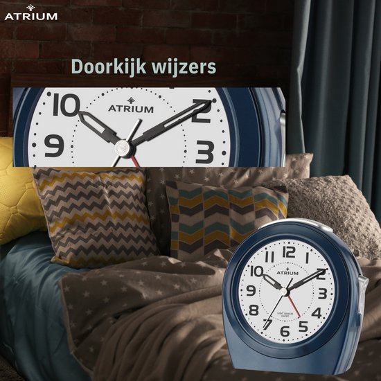 Donkerblauwe wekker op een bed met decoratieve kussens. Close-up van de wijzers.