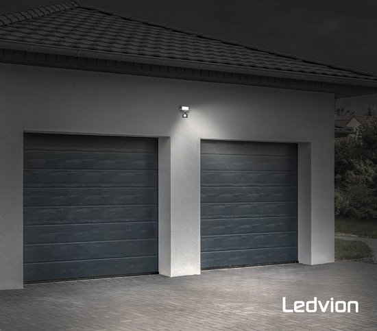 Projecteur LED Ledvion noir illuminant une double porte de garage la nuit.