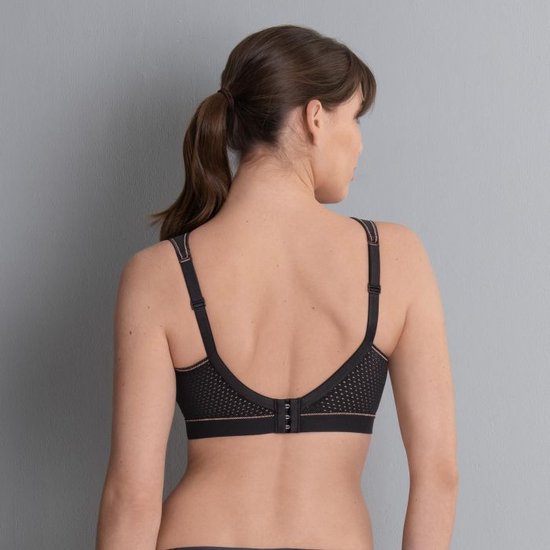 Model van achteren in zwarte sportbeha met koperkleurige biezen.
