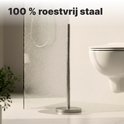 Roestvrijstalen toiletrolhouder in een badkamer met lichte vlekken.