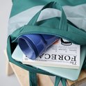 Tasse vert clair et objet bleu dans un sac.