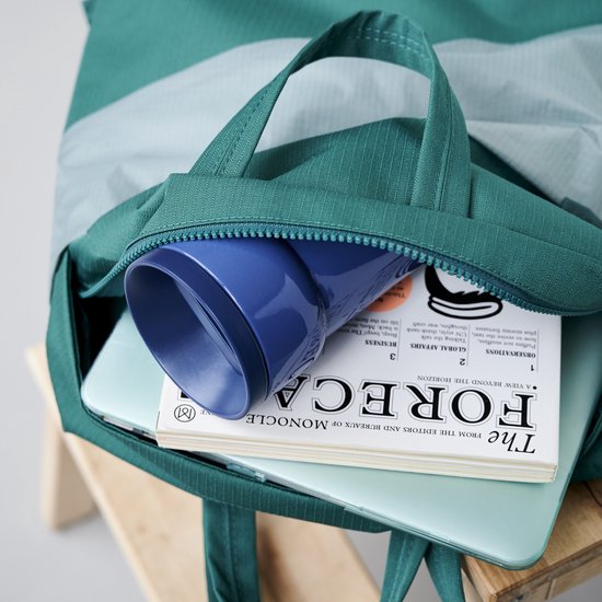Tasse vert clair et objet bleu dans un sac.