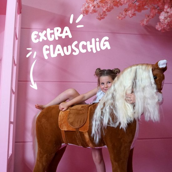 Bruin pluche paard met lange blonde manen en zadel, met een meisje erop. Tekst: "EXTRA FLAUSCHIG".