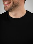Close-up van een man met een zwart Suitable T-shirt, de ronde hals is zichtbaar.